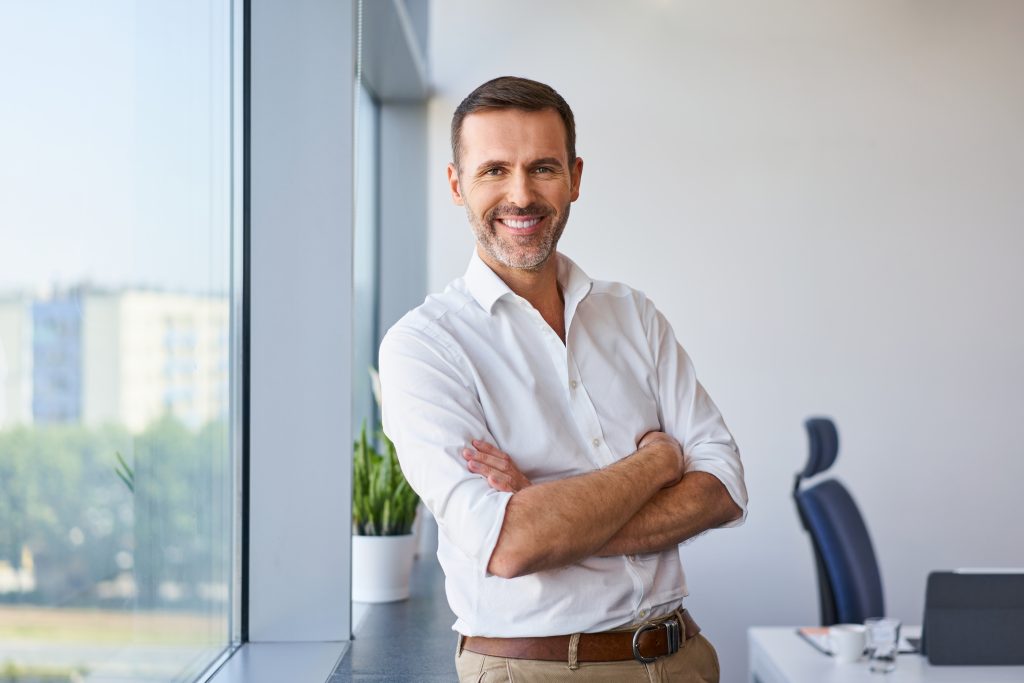 Portrait of smiling adult businessman standing at corporate office