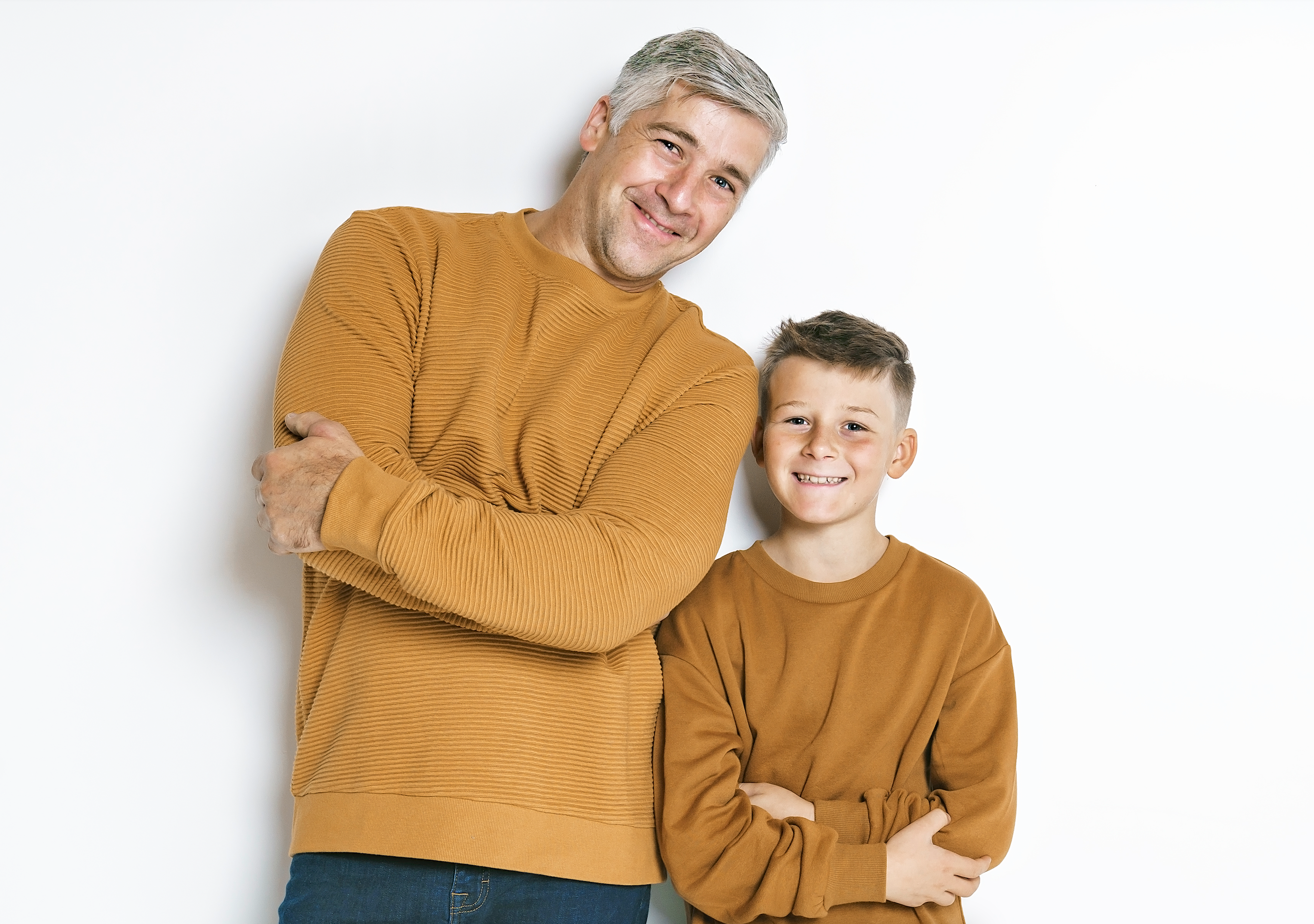 Portrait of a smiling father and young son with their arms crossed isolated on white background