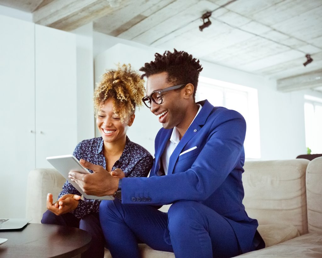 Two business people (man and woman) sitting at a table working on a digital tablet together