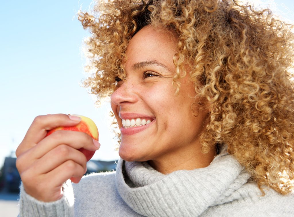 Close up side portrait of healthy young woman holding apple